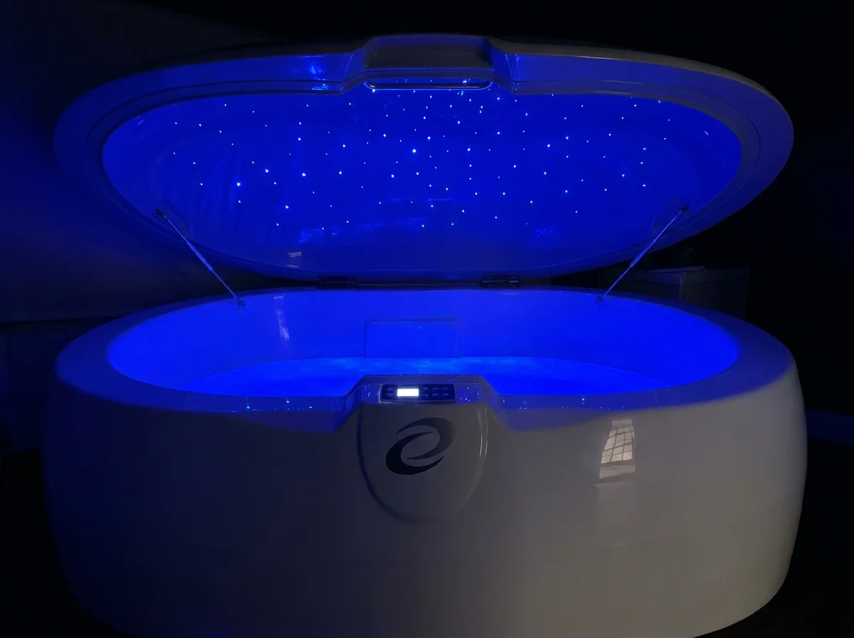 Tanque Infinity de flotación en una sala oscura con cielo de luces